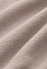 Licht taupe fleece stof met een gestructureerd, zacht oppervlak, met subtiele naden en plooien die een golvende uitstraling creëren.