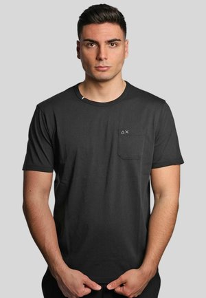 T-shirt nera a maniche corte in cotone, con taschino sul lato sinistro del petto e un piccolo logo, collo rotondo e vestibilità morbida.