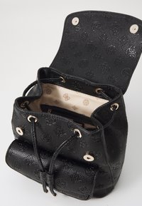 Bolso tipo bucket negro hecho de cuero texturizado, con herrajes dorados, cierre de cordón y un interior con estampado. Forrado en beige claro.