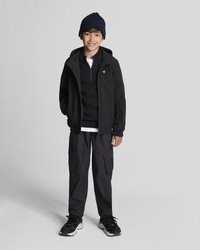 Schwarze Zip-up Jacke über einem schwarzen Sweatshirt, mit einer marineblauen Strickmütze. Schwarze Cargo-Hosen und schwarze Sneakers runden das Outfit ab.
