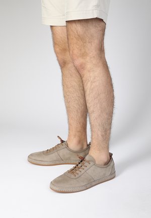 Hellgraue Wildledersneaker mit braunen Schnürsenkeln, minimalistischem Design und Gummisohle. Knöchelhoch mit einer gesteppten Naht am Obermaterial.
