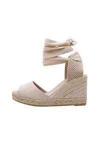 Sandalias beige de cuña con suela de yute trenzado, tiras de tela en el tobillo y un panel trasero texturizado. Diseño de punta abierta con un acabado suave.