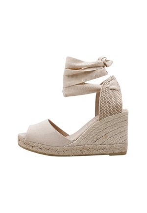 Sandales compensées beiges avec semelle en jute tressé, brides de cheville en tissu et panneau arrière texturé. Design à bout ouvert avec une finition lisse.