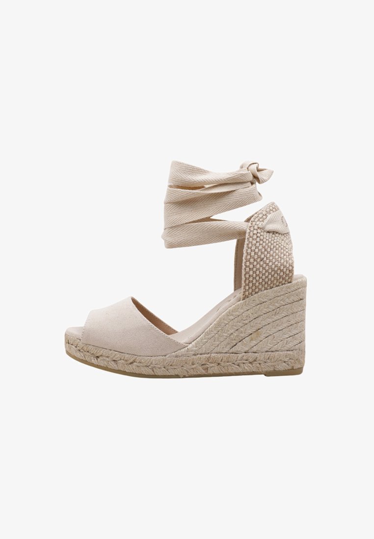 Sandales compensées beiges avec semelle en jute tressé, brides de cheville en tissu et panneau arrière texturé. Design à bout ouvert avec une finition lisse.