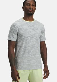 Vaaleanharmaa lyhythihainen t-paita, jossa aaltoileva tekstuurikuosi ja kontrastinen keltainen pääntie. Valmistettu hengittävästä materiaalista.