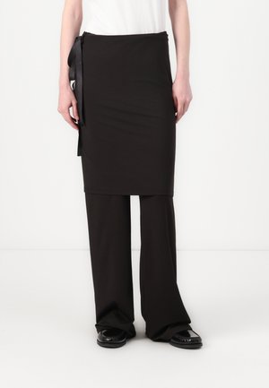 Black two-piece outfit featuring a knee-length skirt with a side tie and wide-leg trousers. Material appears smooth with a matte finish.
