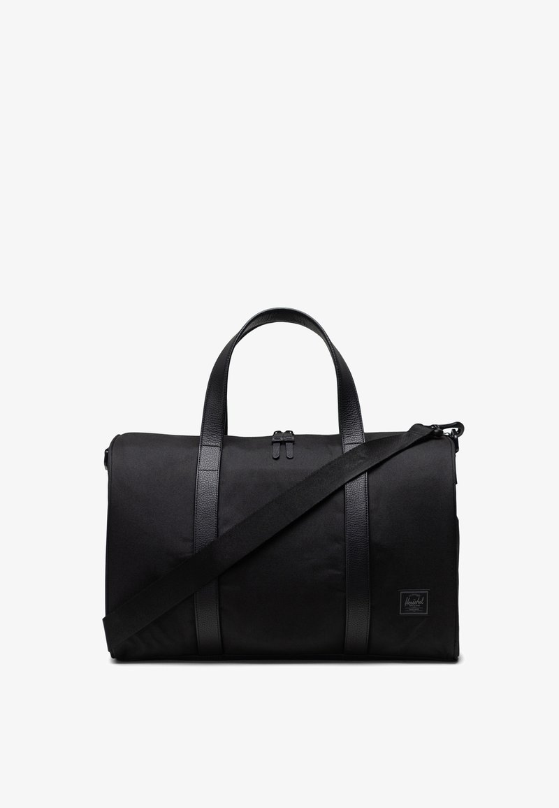 Sac de voyage noir avec un corps en textile, des accents en cuir texturé, des poignées supérieures doubles et une bandoulière réglable. Il dispose d'une fermeture éclair.