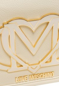 Crèmekleurige lederen portemonnee met een verhoogd goudkleurig hartlogo en 'LOVE MOSCHINO' geperst detail. Gladde textuur met glanzende accenten.