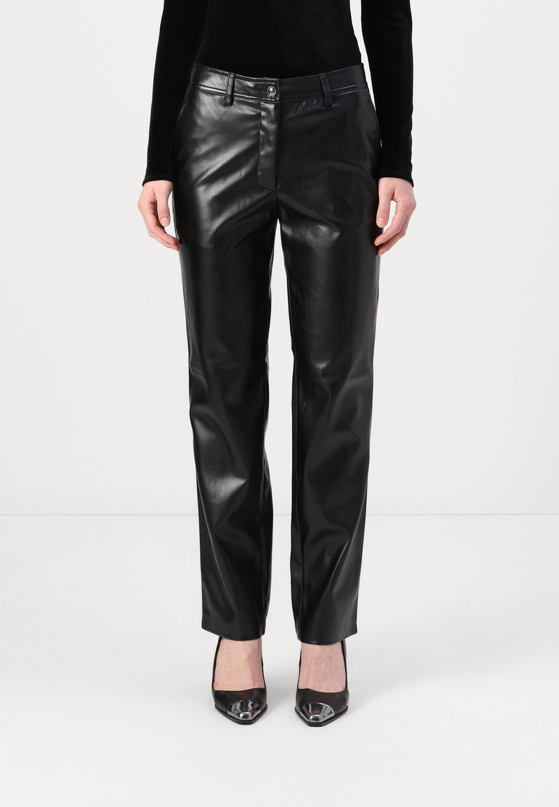 Pantalons en cuir noir avec une coupe droite, dotés d'une fermeture à bouton sur le devant et de poches, associés à des talons aiguilles noirs.