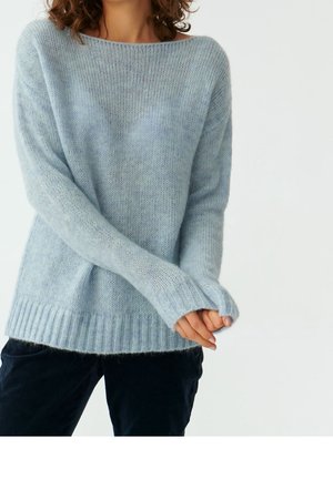 Pull bleu clair surdimensionné avec un large encolure, des poignets côtes et un ourlet côtelé. Texture douce et tricotée avec une apparence légèrement duveteuse.