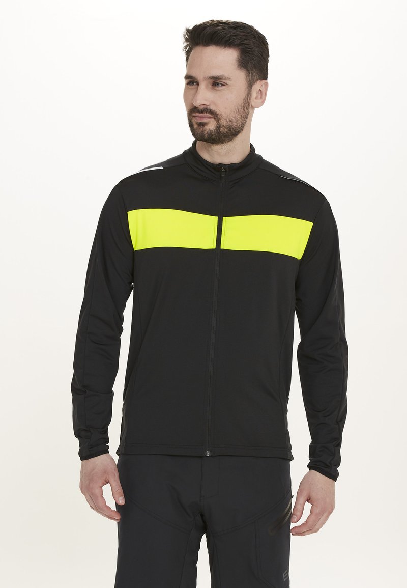 Schwarze Sportjacke mit einem leuchtend gelben horizontalen Streifen über der Brust. Sie verfügt über einen durchgehenden Reißverschluss, lange Ärmel und reflektierende Akzente auf den Schultern.
