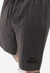 Crne pamučne kratke hlače s elastičnim pojasom i vezicom. Imaju mali crni logo "Lonsdale London" blizu rubova.