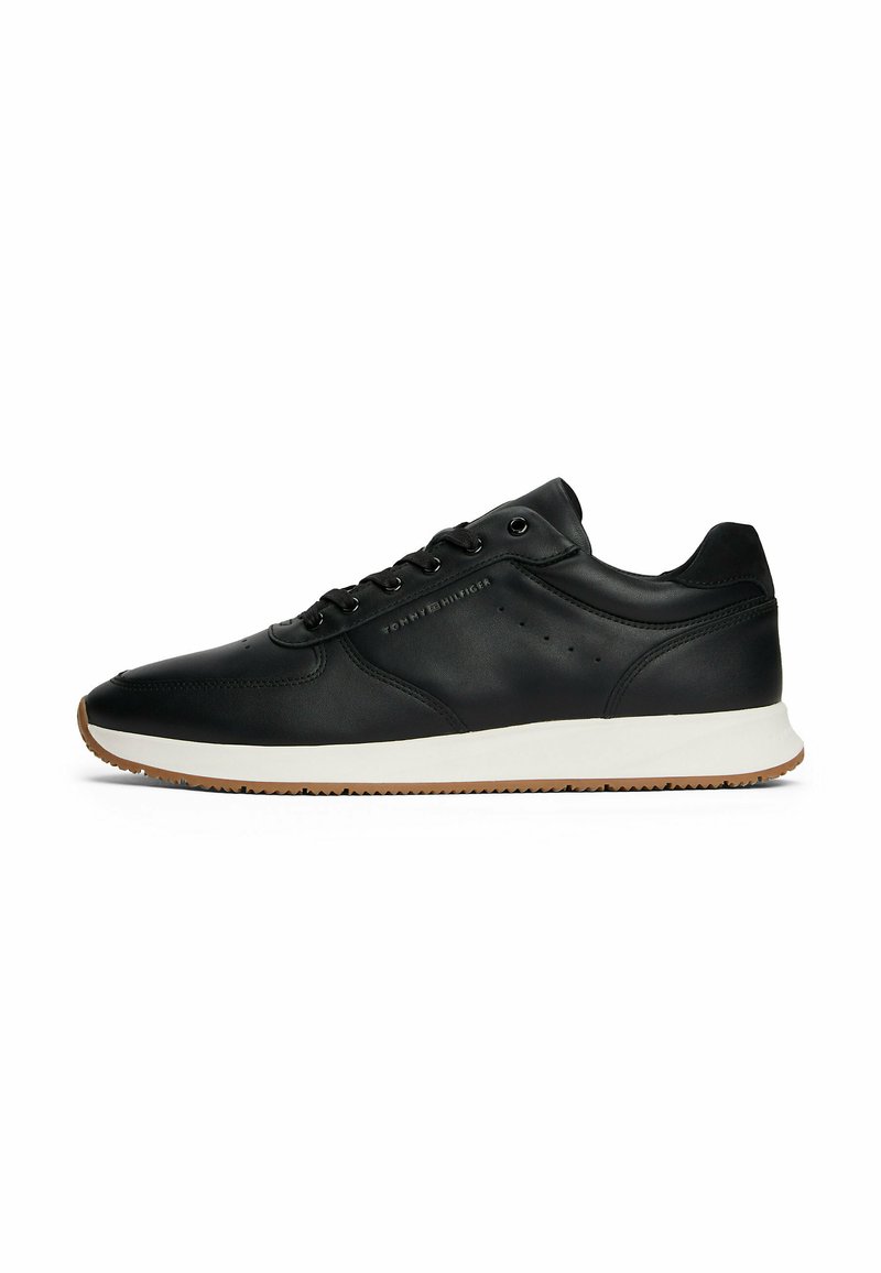 Sneakers in pelle nera con una suola intermedia bianca e suola in gomma color caramella. Presentano sei passanti, dettagli perforati e logo impressa sul lato.