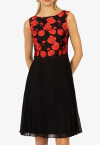 Abito nero a pieghe con corpetto ricamato floreale che presenta rose rosse su uno sfondo nero. Design senza maniche con scollatura tonda.