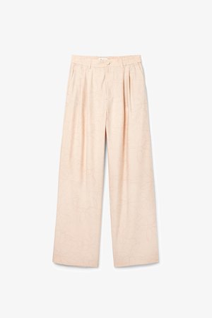 Világos barack színű, bő szabású nadrág finom virágmintával, rugalmas derékrésszel és egy gombos záródással, amely laza siluettet biztosít.