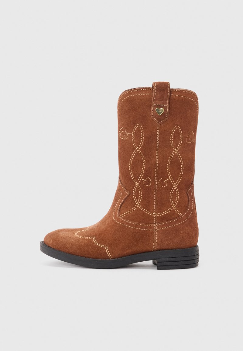 Botín de ante marrón de tobillo con intrincada costura blanca, una pestaña para tirar, un acento en forma de corazón y una puntera redondeada. Suela de goma plana, diseño informal al estilo occidental.