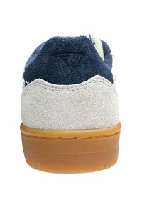 Baskets avec une tige en daim blanc, un talon en daim bleu marine, une semelle en caoutchouc naturel et un logo embossé à l'arrière. Lacets plats et col rembourré.