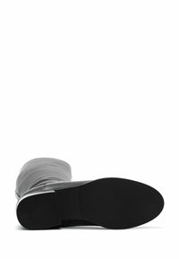 Stivaletto alla caviglia in pelle nera con gambale grigio flessibile, texture liscia, punta arrotondata e suola in gomma texturizzata.