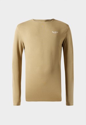 Chemise beige à manches longues en coton avec un col rond. Présente un petit logo blanc sur la poitrine gauche. Texture lisse, design minimal.