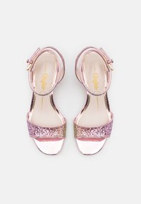 Sandales à talons pailletées en rose et or rose avec une bride à la cheville, présentant une finition métallique brillante et une large bande scintillante sur les orteils.