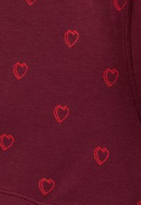 Bordowy materiał z powtarzającym się wzorem małych, czerwonych serduszek z konturem oraz widocznym przeszyciem na krawędzi.