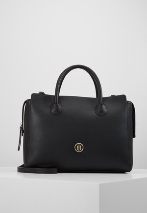 Black leather handbag with dual padded handles, gold-tone logo detail, structured shape, and a detachable shoulder strap. Smooth texture.