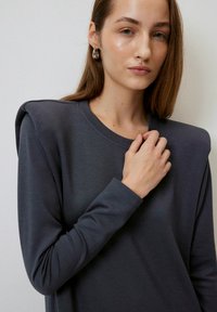 Donkergrijze lange mouw top met een ronde halslijn en schouderaccenten, vervaardigd uit zachte stof met een gladde textuur, gestyled met aansluitende mouwen.