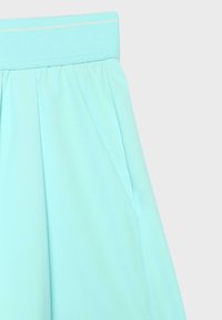 Jupe bleu clair avec une large ceinture et des plis subtils, montrée à partir de la moitié supérieure sur un fond uni.