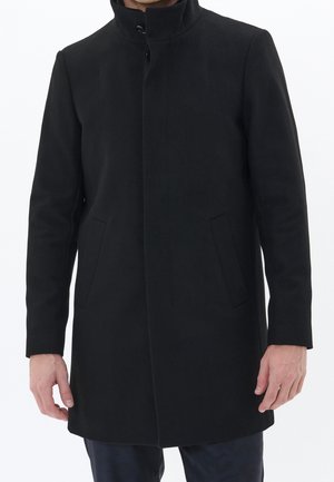 Schwarzer Wollmischmantel mit hohem Kragen, vorderer Knopfverschluss und seitlichen Taschen. Gerader Schnitt mit langen Ärmeln und glatter Textur.