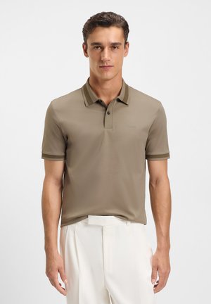 Kaki polo skjorte laget av et glatt, lett stoff. Har en kragehals, korte ermer og kontrastkant. Logo på brystet.