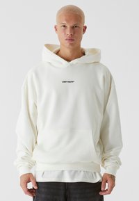 Felpa bianca con cappuccio, caratterizzata da una tasca frontale e il logo "LOST YOUTH" in nero. Realizzata in un tessuto morbido, presenta una vestibilità rilassata e polsini a coste.