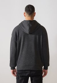 Temně šedá, hřejivá mikina s kapucí a šňůrkou, dlouhými rukávy a volným střihem. Měkká textura a jednobarevný design.