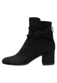 Bottine en daim noir avec talon carré, sanglon enveloppant noué en nœud, et bout arrondi, vue de côté extérieur.