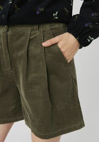 Shorts en velours côtelé vert olive avec des côtes verticales, dotés de poches latérales et d'un design plissé pour un détail supplémentaire.