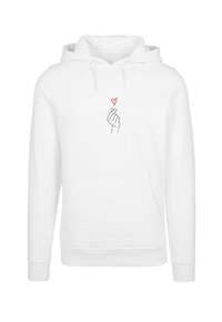 Biela mikina s kapucňou, ktorá má predné vrecko, s grafikou ruky robenej do srdcového gesta v čiernej farbe a malým červeným srdcom nad ňou.