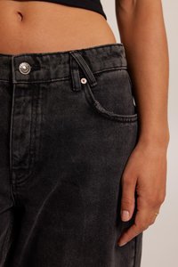 Black denim jeans with a classic cut, featuring a front button, pockets, and subtle stitching details. Smooth texture, medium weight fabric.