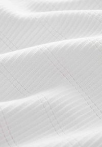 Tissu blanc texturé présentant un motif à grille subtil avec de fines crêtes verticales et horizontales, créant un aspect doux et stratifié.