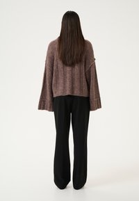 Mauve cropped sweater with ribbed texture and bell sleeves, paired with black wide-leg trousers, viewed from the back.