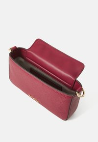 Borsa in pelle borgogna con superficie testurizzata. Design aperto che rivela un interno solido e un compartimento con zip per l'organizzazione. Accenti in hardware dorato.