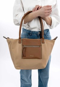 Borsa tote beige realizzata in materiale resistente con dettagli in pelle marrone. Presenta una tasca con zip frontale, manici doppi e dettagli di cucitura bianca.