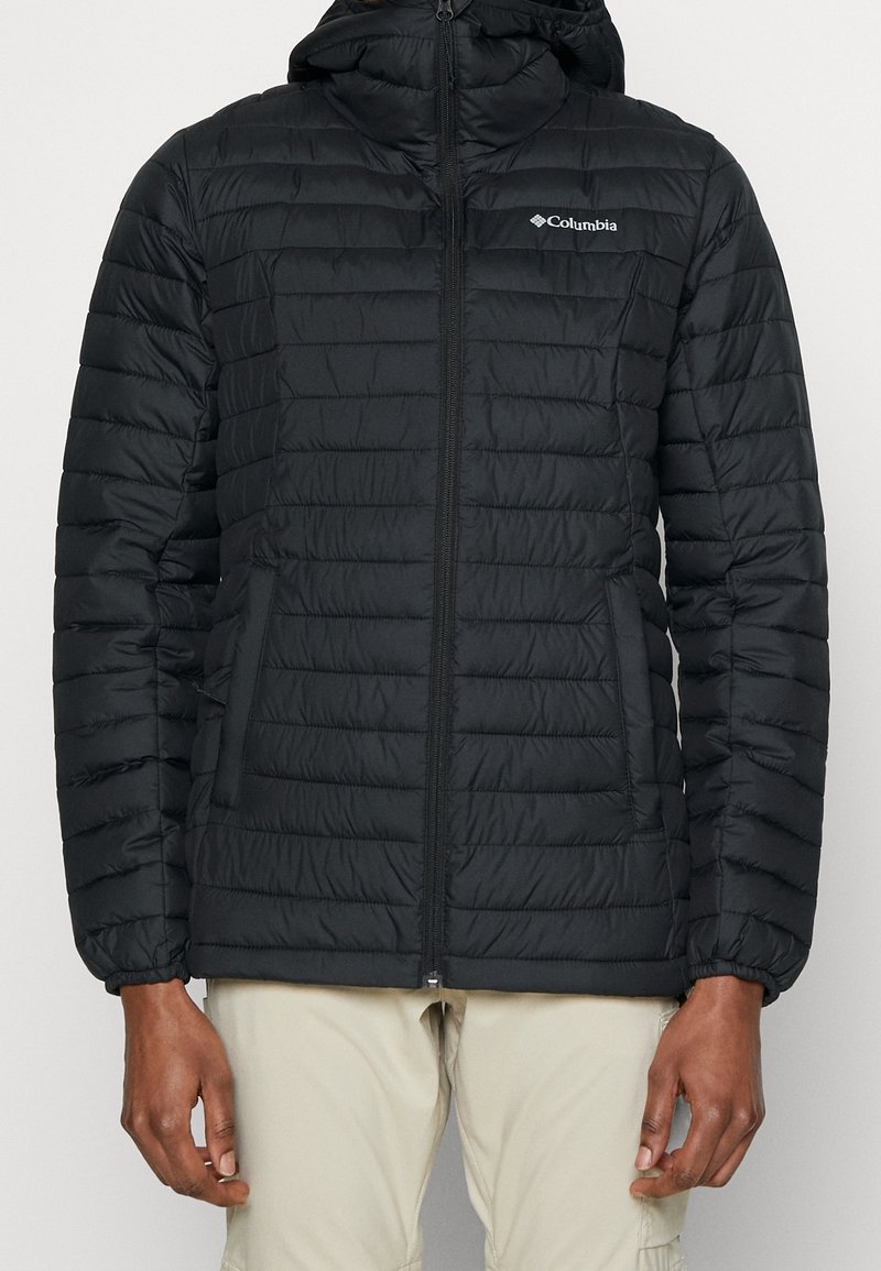 Giacca invernale nera isolata con zip frontale, polsini elasticizzati e cappuccio. Presenta un design a quadri orizzontali e il logo Columbia sul petto.