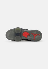 Semelle de chaussure avec une semelle grise, comportant le logo rouge Nike Air et la silhouette rouge du joueur de basketball Jumpman sur un fond blanc.