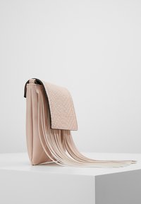 Pinkfarbene Clutch-Tasche mit einer strukturierten Klappe und langen Fransenakzenten. Hergestellt aus weichem Material mit glatter Oberfläche und rechteckiger Form.