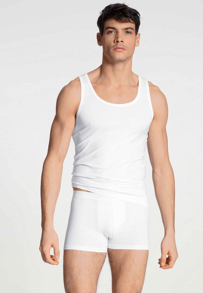 Un débardeur en coton blanc et un shorty sur un modèle, présentant un design ajusté, une texture lisse et un style simple et dépouillé.