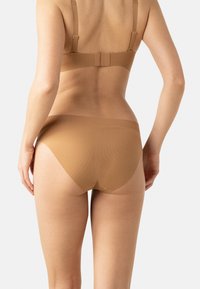 Ensemble soutien-gorge et culotte dans une teinte marron clair. Le matériau est lisse et côtelé, avec des bretelles réglables et des bords sans couture pour une visibilité minimale.
