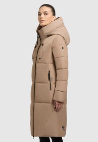 Beige polstret lang jakke med højt krave, justerbar hætte, sidelommer med lynlås og et trekantet logo på kanten. Glat, vandafvisende stof.