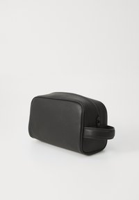 Trousse de toilette en cuir noir avec une finition texturée, de forme rectangulaire, et une poignée latérale. Comprend une fermeture éclair sur le dessus pour un maintien sécurisé.