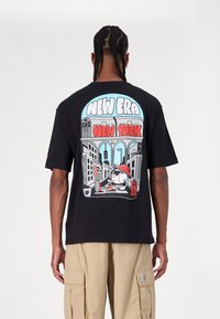 Μαύρη κοντομάνικη μπλούζα με πολύχρωμο γραφικό σχέδιο στην πλάτη, που περιλαμβάνει το κείμενο "NEW ERA" και "NEW YORK", καθώς και έναν καρτούν χαρακτήρα.