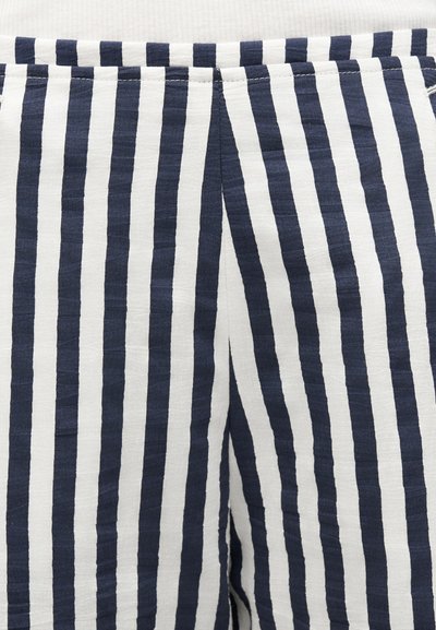 Ύφασμα με κάθετες ρίγες σε ναυτικό μπλε και λευκό με κεντρική ραφή, πιθανώς μέρος ενός ενδύματος όπως παντελόνια ή σορτς.