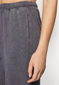 Kolkgrå sweatpants med ribbad textur, som har sidofickor och en liten, mörk broderad logotyp på vänster lår.